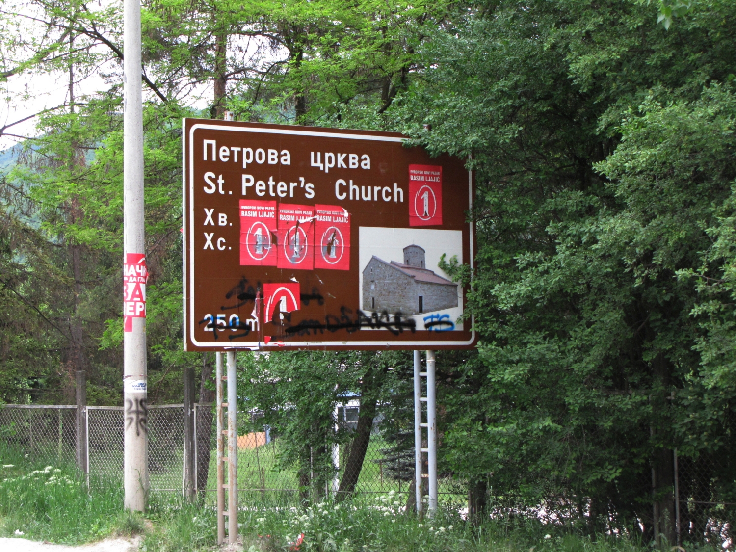 Street sign informing about anciet st. Peter church - partly covered by Muslims