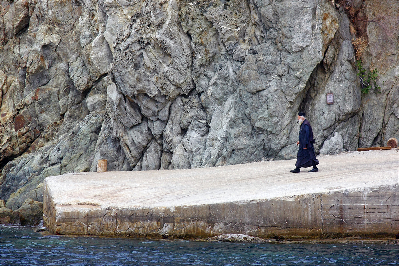 A monk strolling on the dock of the Athos monastery of Agiou Grigoriou 